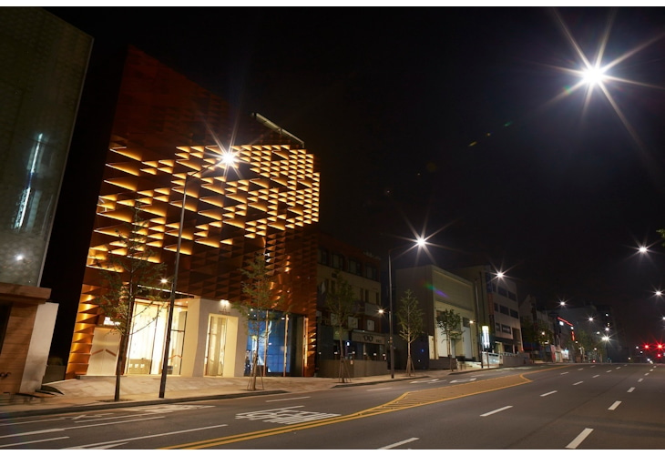 Gangnam's seven-story Johnnie Walker House has a striking copper exterior that reflects light during the day and transforms into a whisky bottle at night. Inside, visitors can explore a retail space, rooftop bar, club, VIP whiskey lounge, cocktail school, and a whiskey-themed restaurant with interactive technology and whiskey-inspired design. Design by Studio Königshausen.